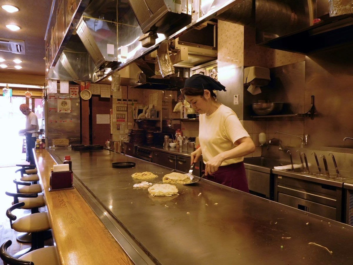 Okonomiyaki, the local speciality, consists of layers of cabbage, pork, squid sandwiched between a thin pancake and a this omelet